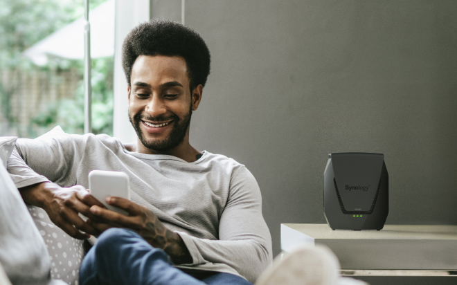 Person using phone with a Synology router nearby